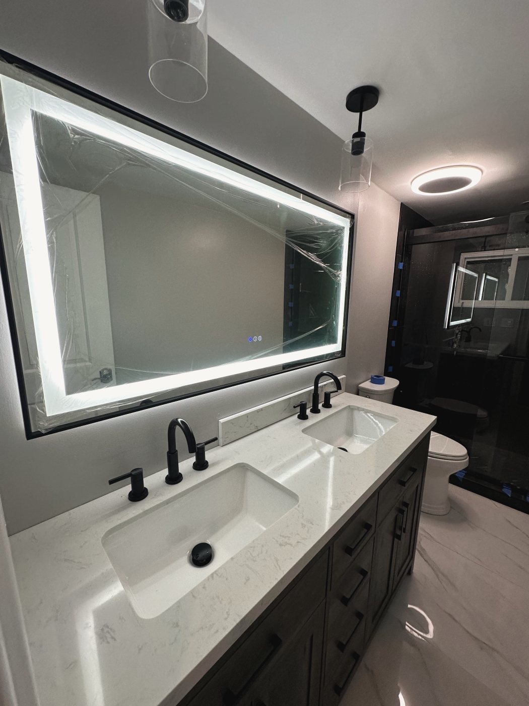 Double vanity with lit mirror and black fixtures